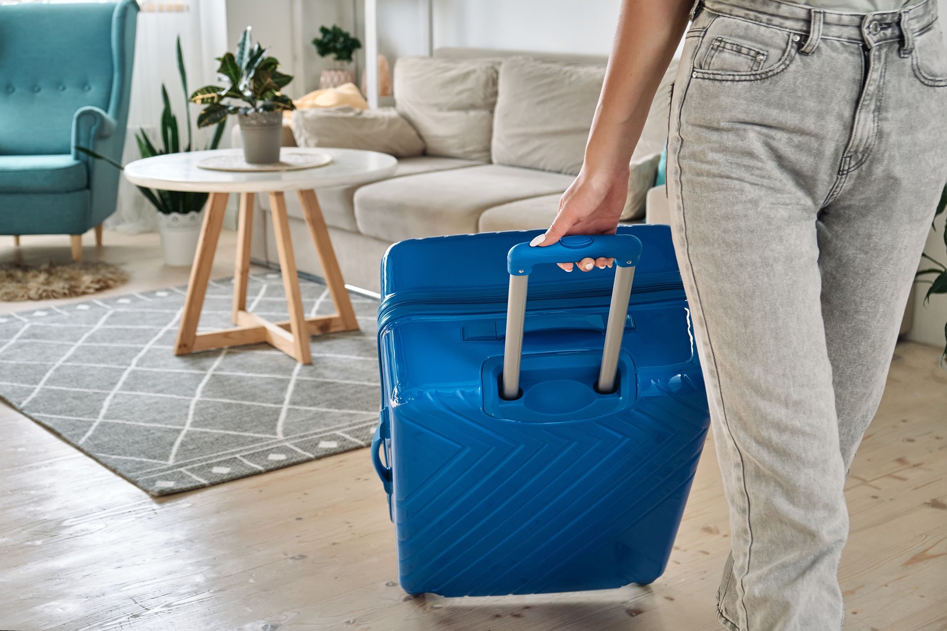 Unrecognizable woman leaving home with a suitcase going on a trip or vacation